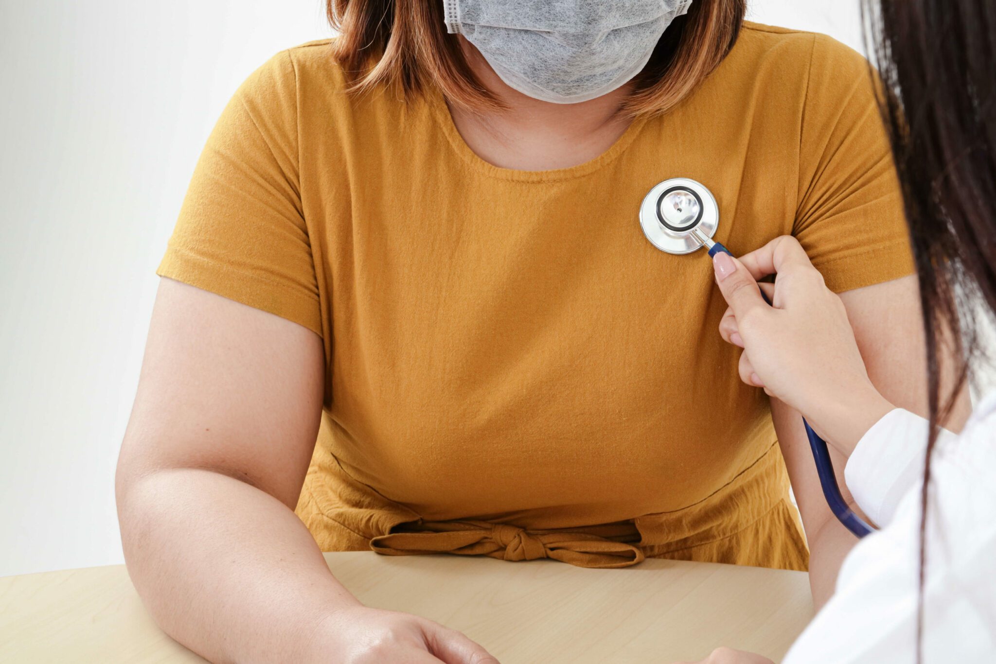 A heakth provider listening to a woman's heart beat