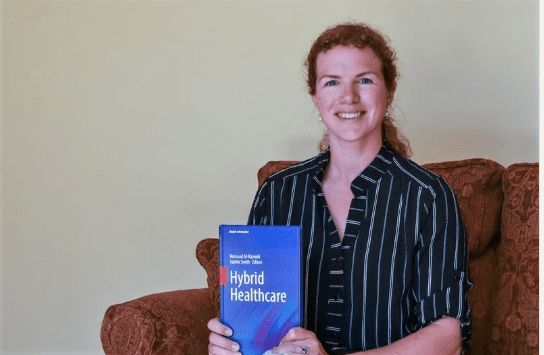 A woman holding a book on Hybrid healthcare